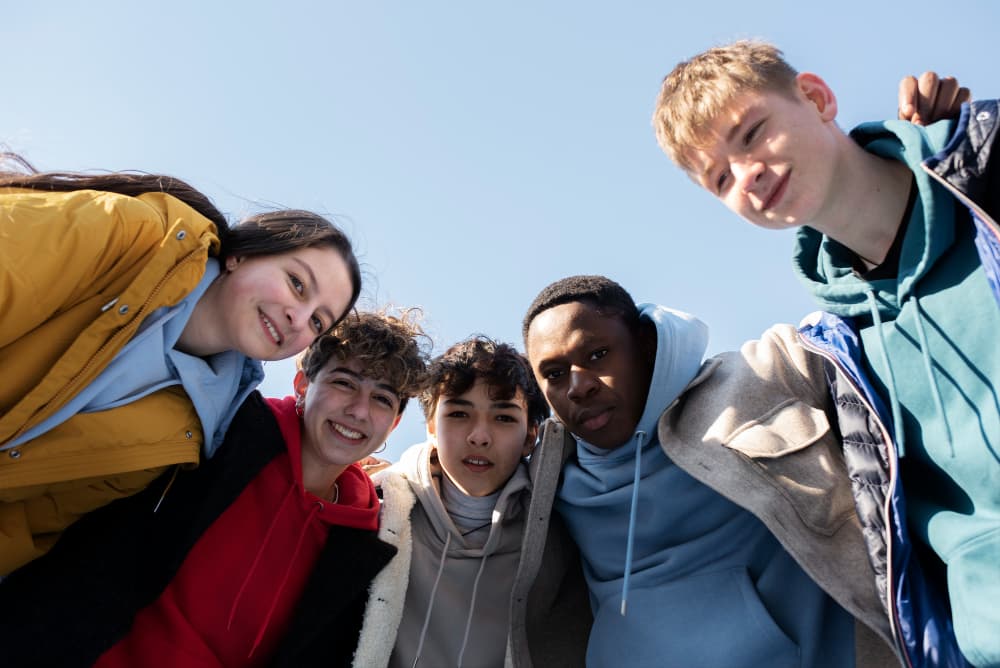 Une adolescente utilise l'application Mélio sur son téléphone, avec en arrière-plan le tableau de bord établissement et des indicateurs d'analyse par l'IA